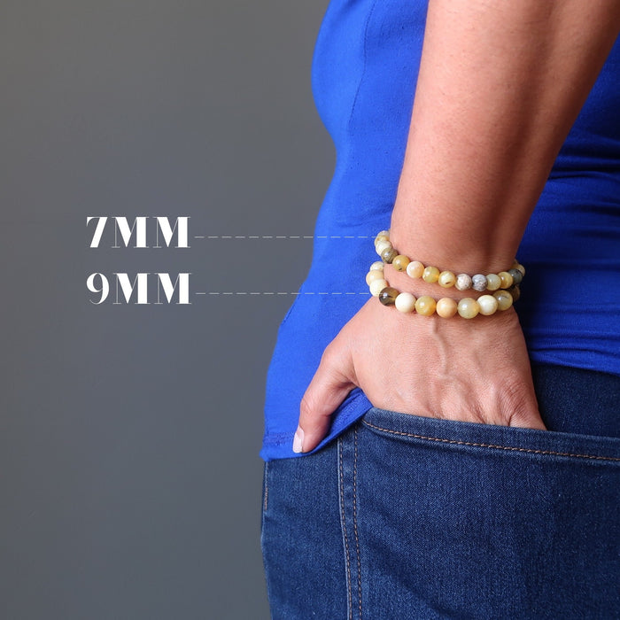 hand in back jean pocket wearing two round yellow opal beaded stretch bracelets