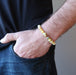 hand in jeans pocket wearing a round yellow opal beaded stretch bracelet