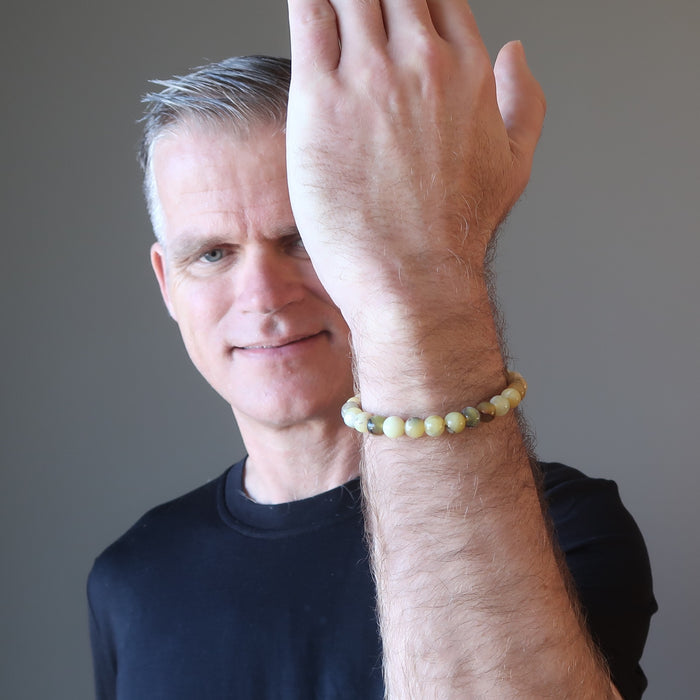 ryan of satin crystals holding up a hand wearing a round yellow opal beaded stretch bracelet