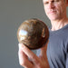 man holding petrified wood sphere
