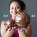 woman holding two petrified wood spheres
