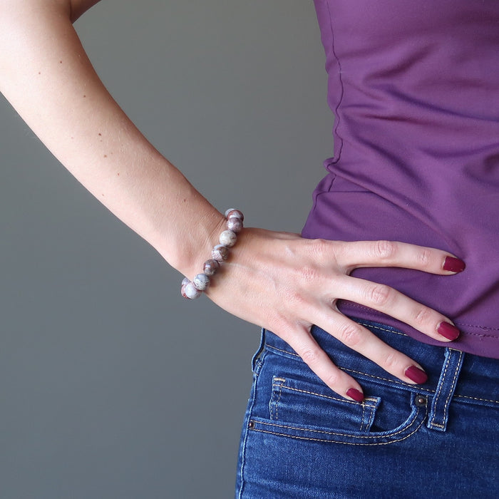 round beaded red mosaic Pietersite bracelet on female model as she holds hand to hips and wears matching red nail polish