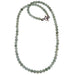 A beaded Prehnite necklace in grassy green color with black Tourmaline inclusions, displayed on a white background.