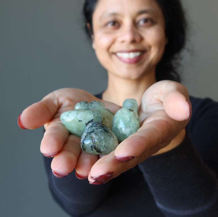woman holding prehnite tumbled stones