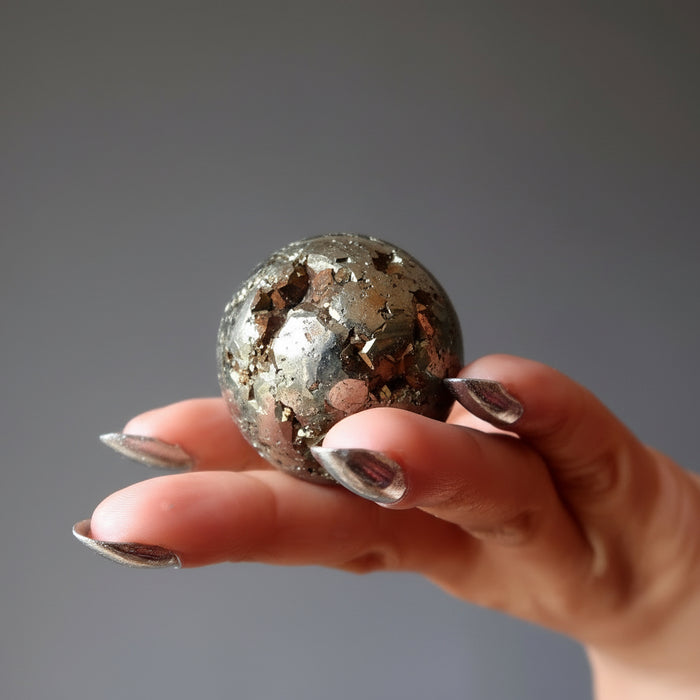 hand holding gold pyrite geode sphere