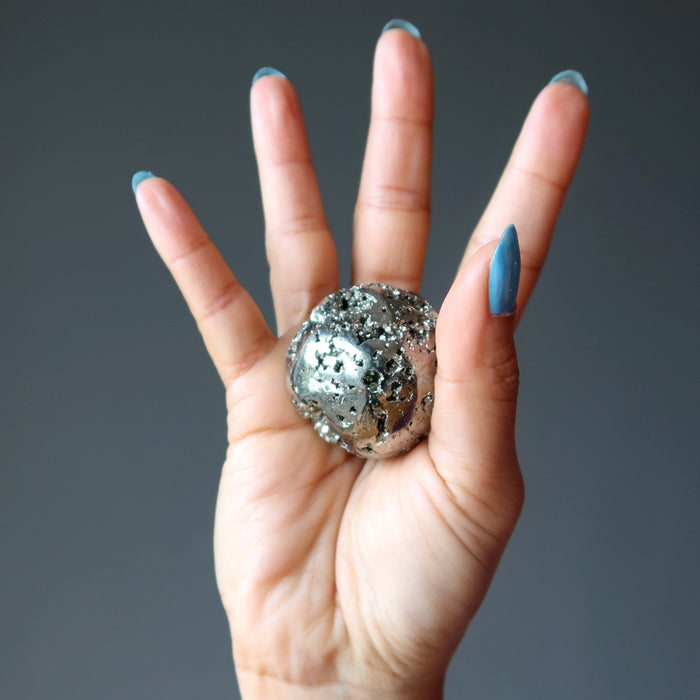 hand holding gold pyrite geode sphere