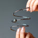 hands showing the coils of faceted pyrite on 3 coils of gunmetal beaded memory wire bracelet