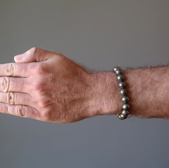 mans hand wearing round pyrite beaded stretch bracelet