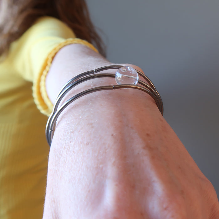 Triple memory coil bracelet with a clear quartz bead ball on a lady's wrist