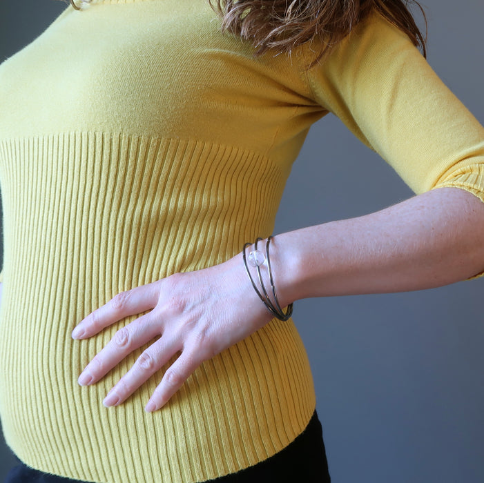 Triple memory coil bracelet with a clear quartz bead ball on a lady's wrist