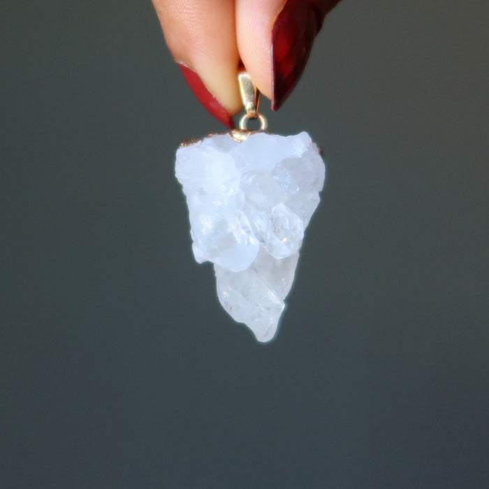 hand holding raw quartz cluster pendant in gold electroplating