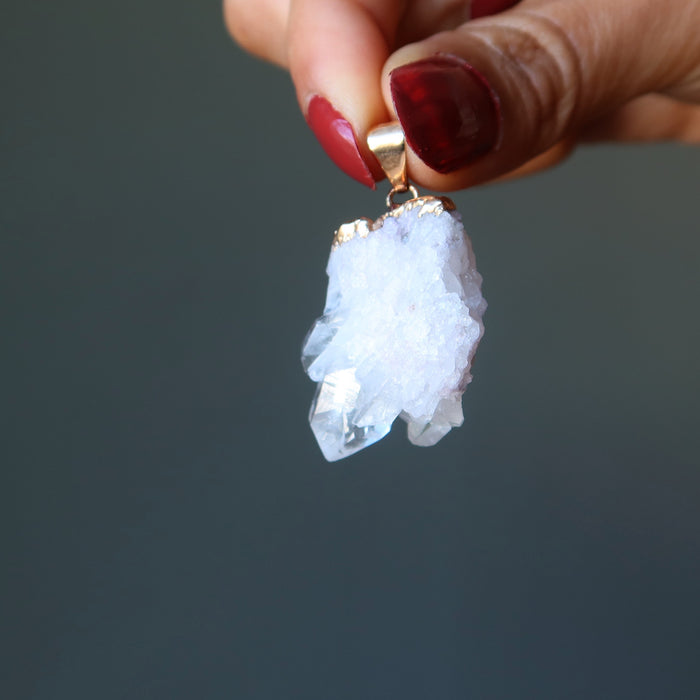 hand holding raw quartz cluster pendant in gold electroplating