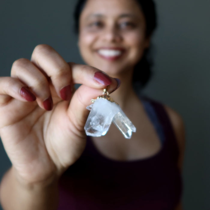 hand holding raw quartz cluster pendant in gold electroplating