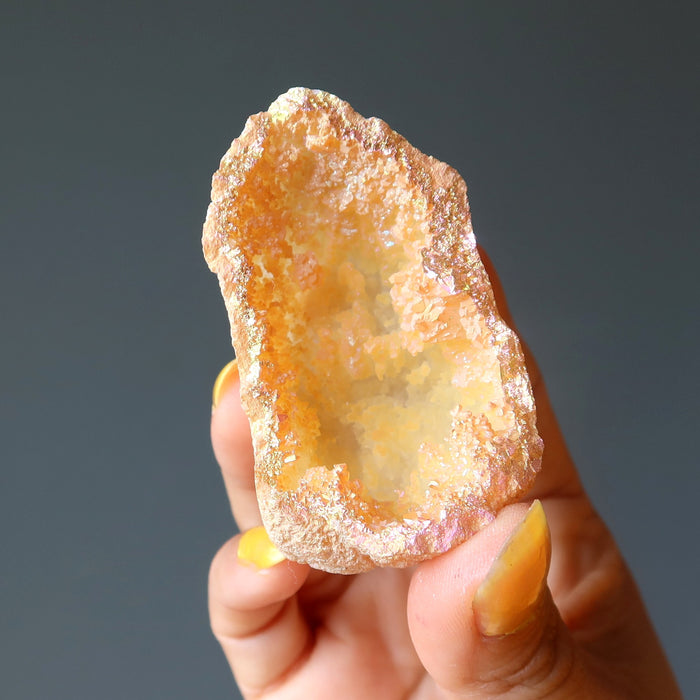 hand holding rainbow aura quartz geode