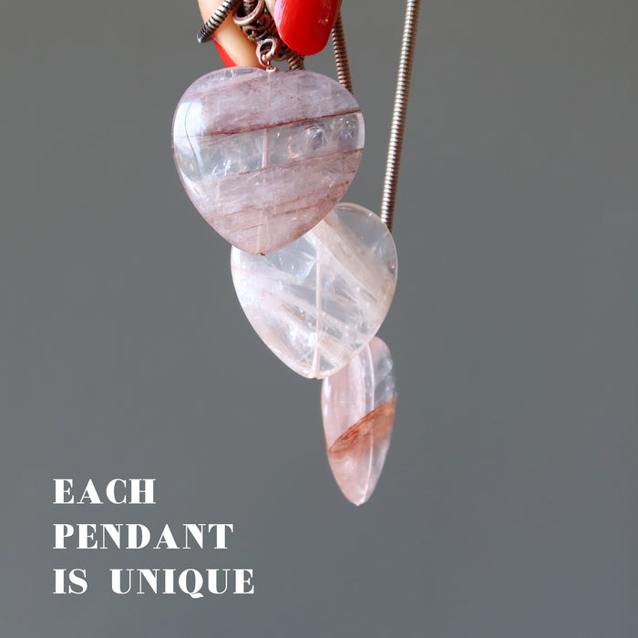 hand holding three fire quartz pendants to show each is unique