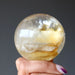 hand holding a golden quartz sphere