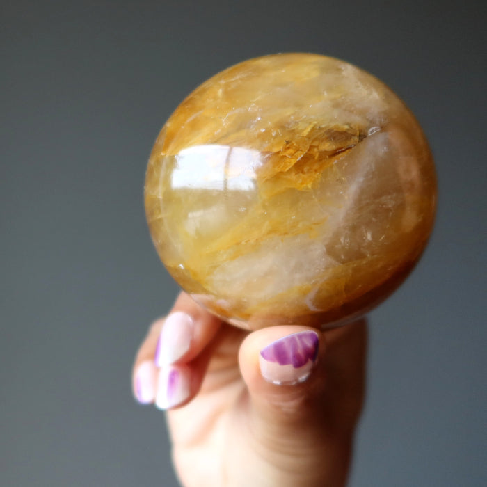 hand holding a golden quartz sphere
