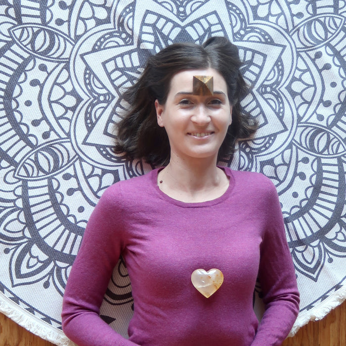 placing Golden Quartz Heart on female model chest with pyramid on the forehead