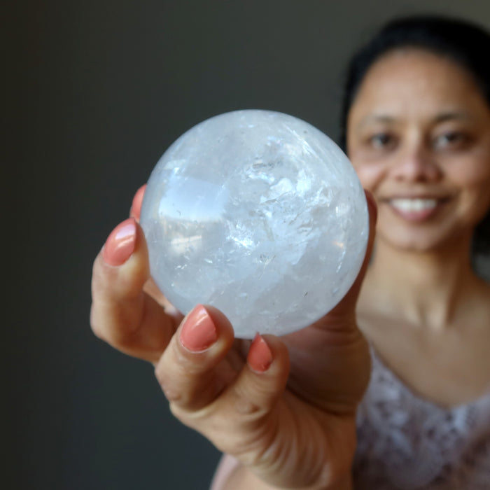 hand holding a clear quartz rainbow sphere