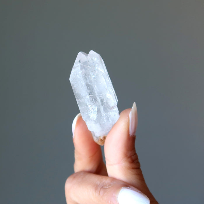 holding one raw clear quartz point