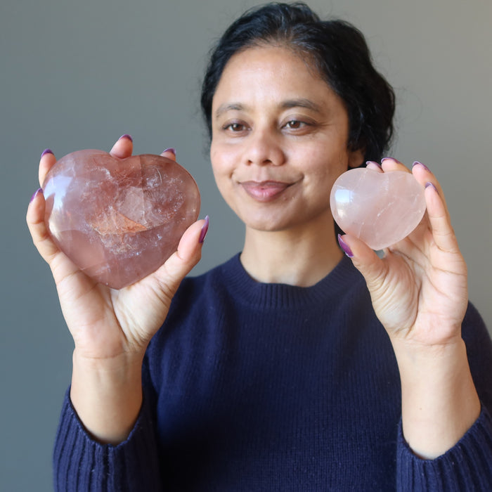 woman holding two red fire quartz hearts
