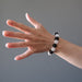 woman's hand wearing white quartz and black obsidian round beaded stretch bracelet