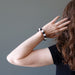 jamie of satin crystals with hand on head wearing white quartz and black obsidian round beaded stretch bracelet