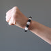 woman's hand making a fist wearing white quartz and black obsidian round beaded stretch bracelet