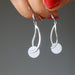 hand holding snow quartz dangle earrings