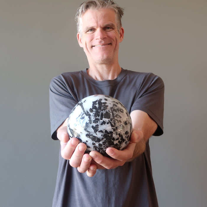 ryan of satin crystals holding a tourmaline quartz sphere