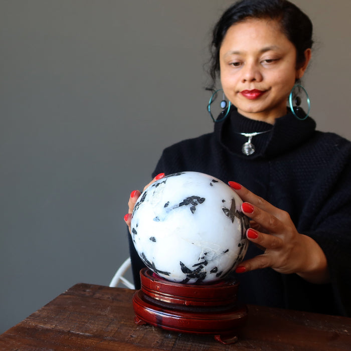 sheila of satin crystals sitting with hands on a quartz tourmaline sphere for gazing