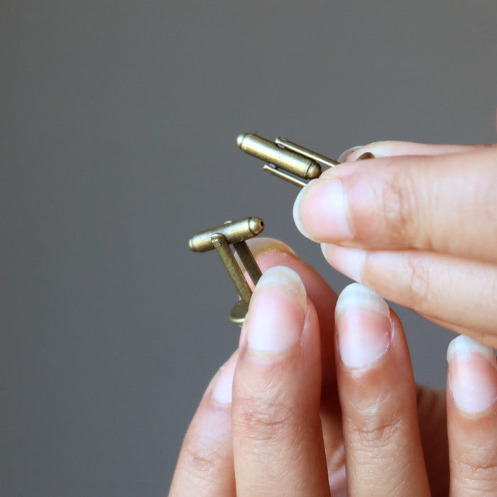 hands holding rhodochrosite cufflinks