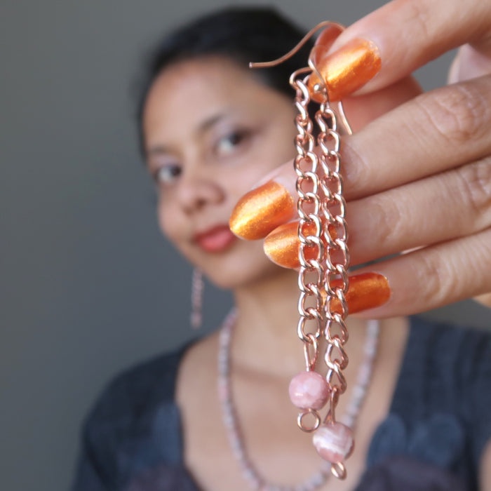 woman holding rhodochrosite copper dangle earrings