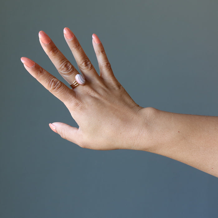 hand wearing rhodochrosite oval in gold adjustable ring