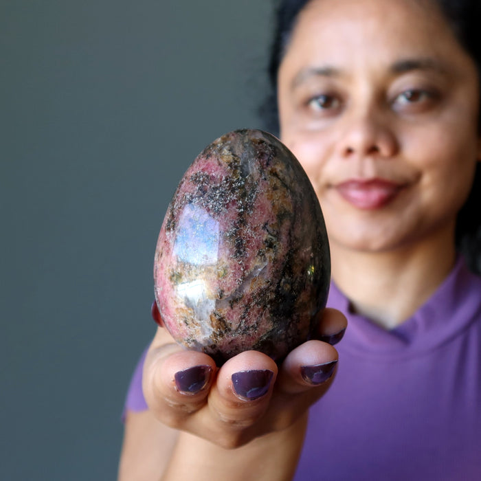 woman admiring rhodonite egg