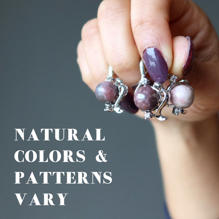 hand holding 3 rhodonite pendants to show natural colors and patterns vary