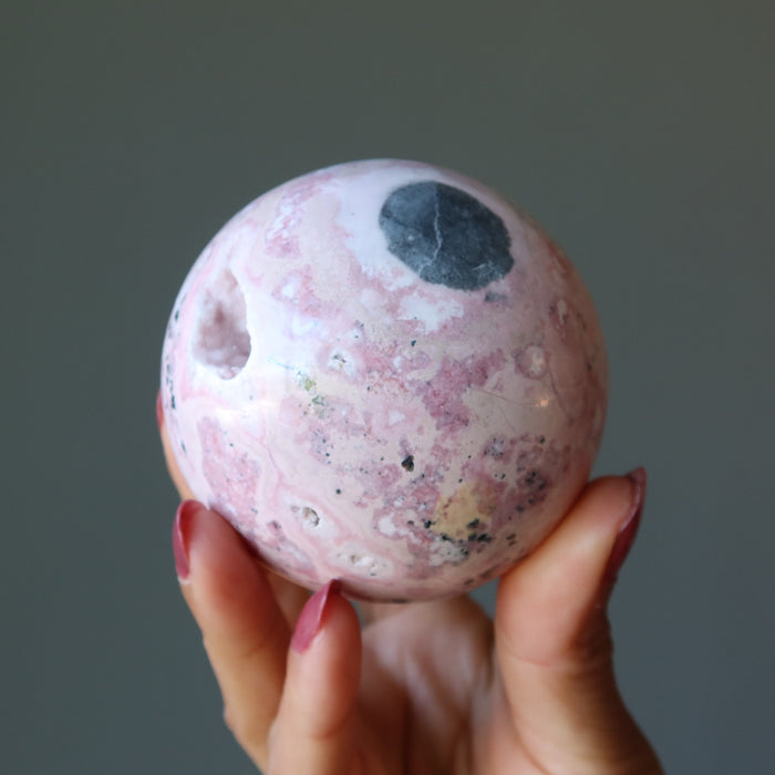 rhodonite geode sphere in hand