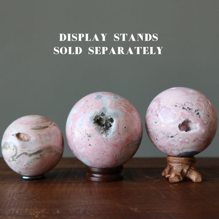 three rhodonite geode spheres on stands