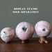 three rhodonite geode spheres on stands