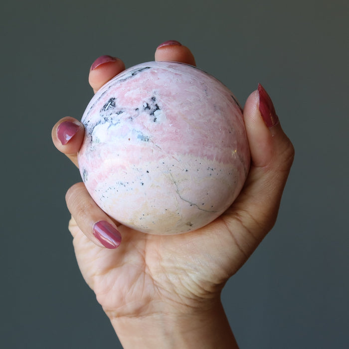peruvian rhodonite sphere in hand