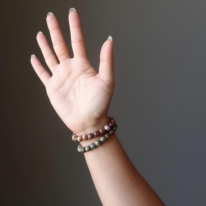 tropical red and green rhyolite bead stretch bracelet pair being modeled on a hand