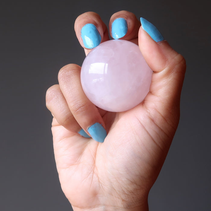 hand holding pink rose quartz crystal ball