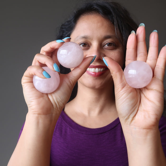 sheila of satin crystals holding up three rose quartz spheres