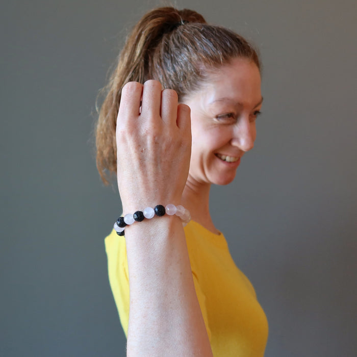 woman smiles as she wears pink rose quartz and black lava combination bracelet