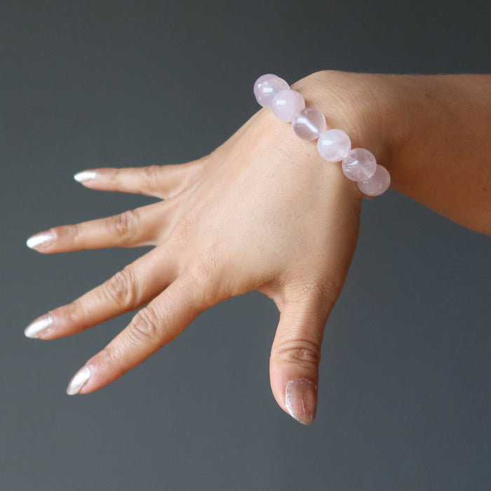 hand wearing clear pink rose quartz round beaded stretch bracelet