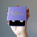 hand holding rose quartz leverback earrings in purple satin crystals box