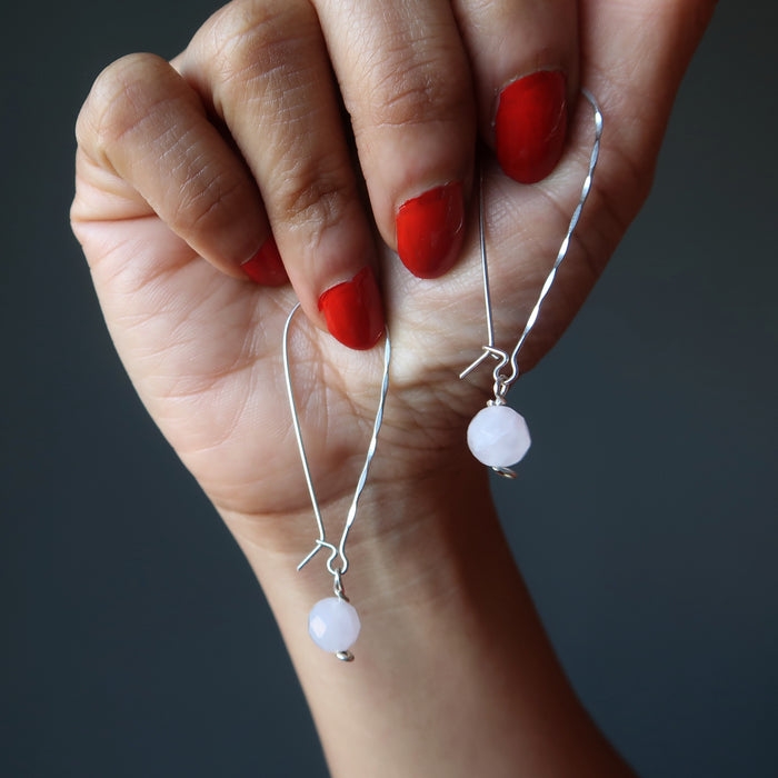 hand holding faceted rose quartz on hammered sterling silver earrings