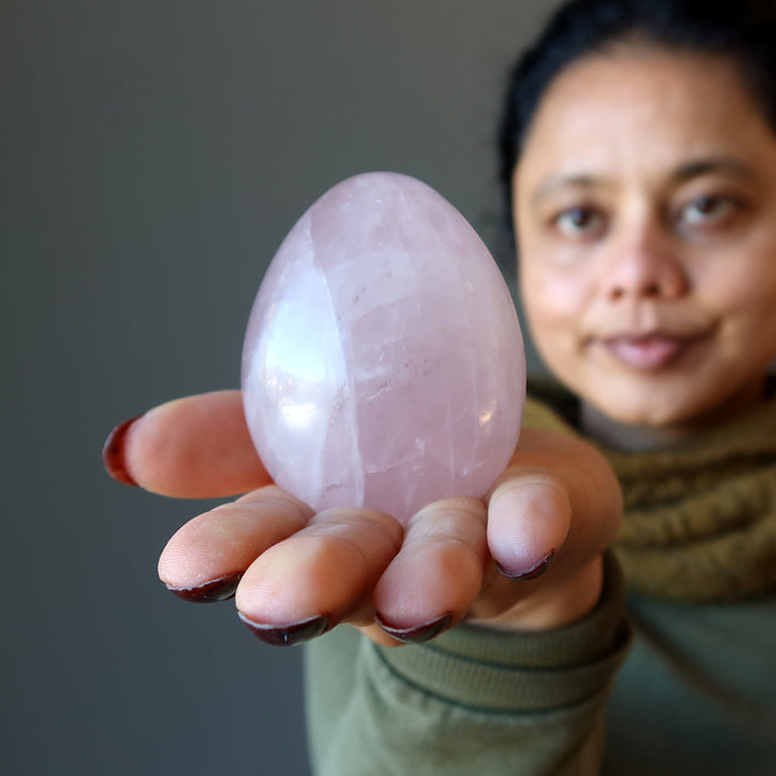 woman gazing at pink rose quartz egg