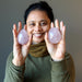woman holding pink rose quartz eggs in palms
