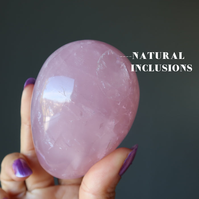 hand holding dark pink star rose quartz egg upside down